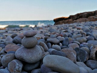 Set of stones on a stone beach with the sea and waves in the background