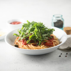 Pasta with tomato sauce, capers and arugula
