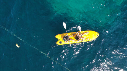 Aerial drone photo of fit young couple practising on a yellow canoe in turquoise open ocean bay with crystal clear sea