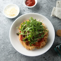Pasta with tomato sauce, capers and arugula