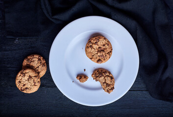 cookies with chocolate shavings on top of a plate on a black background.
