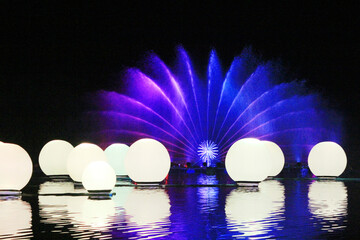 An exhibit showing water and light at night It uses colored balls and fountains behind it and uses spotlighting techniques to enhance its beauty.

