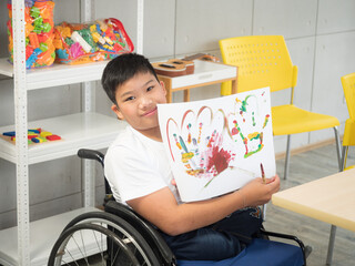 The disabled child in the wheelchair is showing his painted image proudly in the spacial classroom..