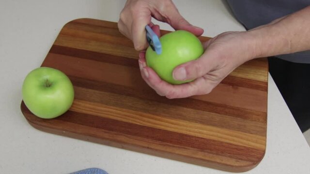 Hands peeling green apple with peeler