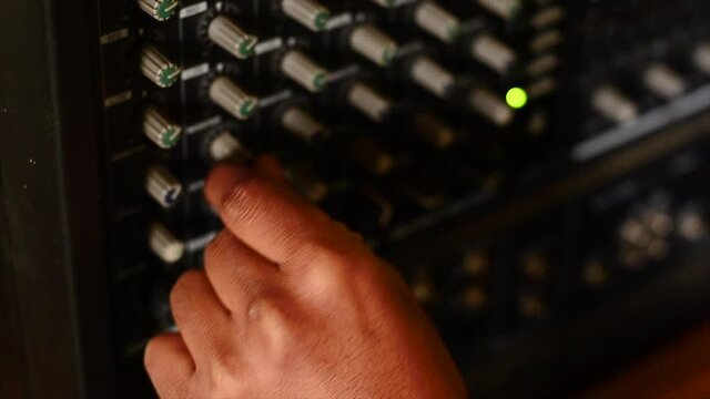 Hands turning knobs to an electric amplifier.
