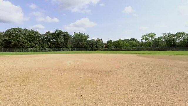 Aerial view from home plate to second base exposing the outfield in an empty softball filed located in the country on a summer day.