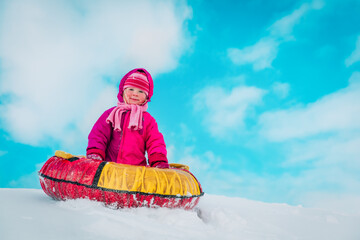 happy cute little girl slide in winter snow