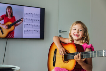 cute girl having guitar lesson online at home
