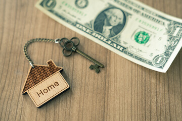 Home key with house keyring on dollar bill stack