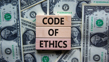 Concept text 'code of ethics' on wooden blocks on a beautiful background from dollar bills.