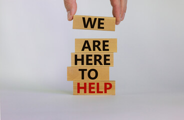 Wooden blocks with text 'we are here to help'. Male hand. Beautiful white background, copy space. Business concept.