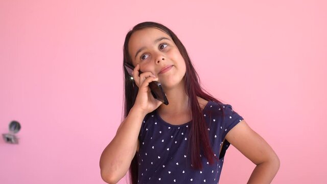 Cute little girl preschool child using a smartphone, looks telephone. Plays in the phone. Children tech addiction concept play game