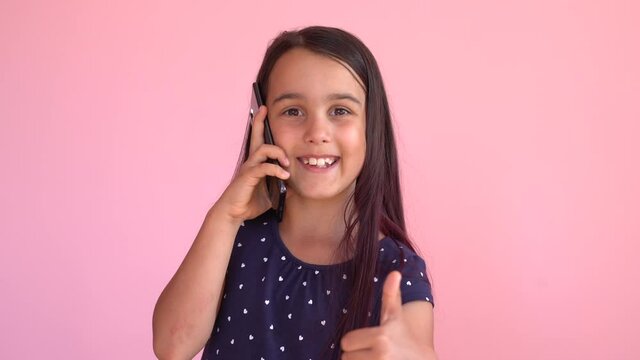 Cute little girl preschool child using a smartphone, looks telephone. Plays in the phone. Children tech addiction concept play game