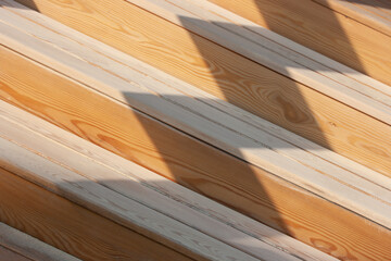 Background from light wooden slats and shadows on them diagonally