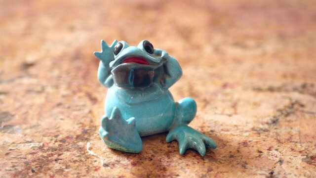 Ceramic blue frog figurine in sunlight.