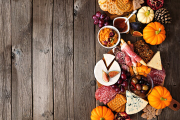 Fall theme charcuterie side border against a dark wood background. Selection of cheese and meat...