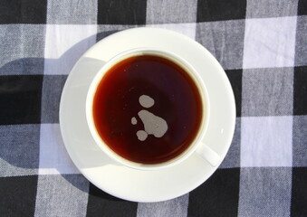 Black coffee or tea in a white cup.  Black and white plaid fabric