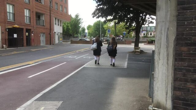 two school girls walking slowly away from camera