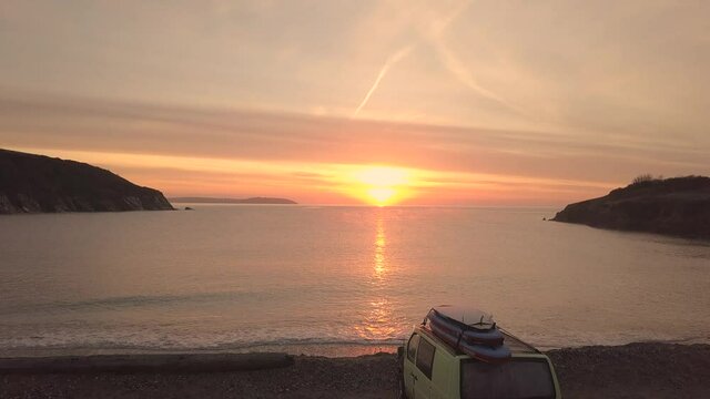 Enjoying the amazing, early morning sunrise by the beach in England waiting in my van with my surfboards on the roof.