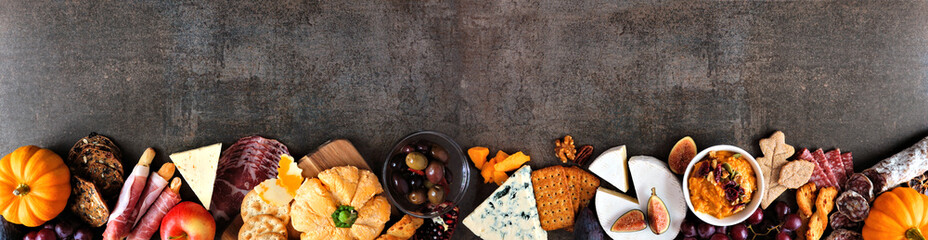 Fall charcuterie border against a dark stone banner background. Assorted cheese and meat...