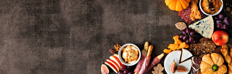 Autumn charcuterie corner border against a dark stone banner background. Selection of cheese and...