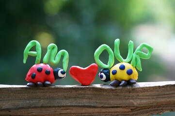 Figurines of two ladybirds made of plasticine. Next to it is the inscription love in French.