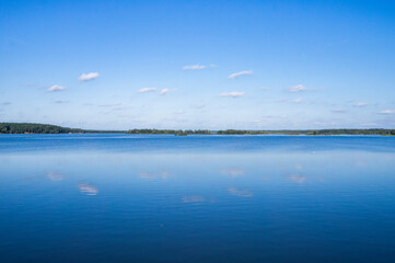 Fototapeta na wymiar Beautiful calm blue landscape with lake view and reflecting sky in water
