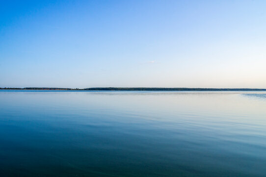 Beautiful calm blue landscape with lake view and reflecting sky in water