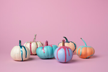Autumn layout made of colorful pumpkins with dripping paint on pink background. Minimal Fall or...