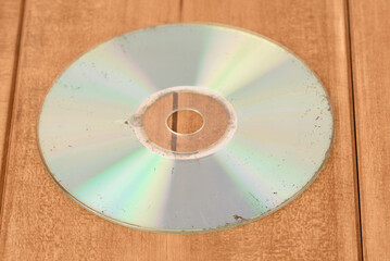 Old scratched worn out cd on the wooden table.