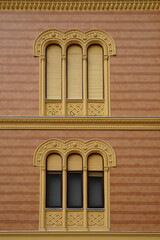 Windows with opened and closed shutters on the renovated yellow building