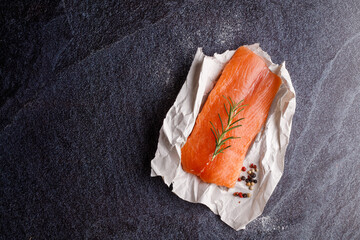 Fresh salmon filet and spices on a concrete black background. Ingredients for cooking.