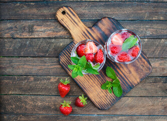 Refreshing summer drink with strawberry and mint  in glasses on rural vintage wooden table. Top view.