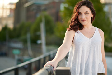Stunning young woman poses for photo in late summer in elevated urban park - white blouse