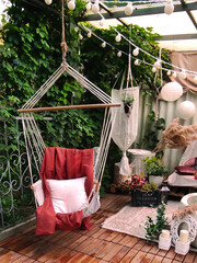 Wicker swing in the garden with red cape and white pillow