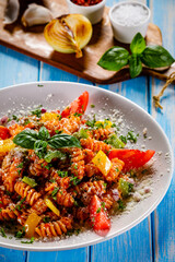 Fusilli with tomato sauce, meat and parmesan on wooden table

