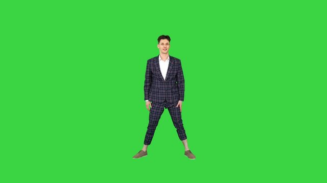 Young attractive male dancer in the strict business suit dancing making a split on a Green Screen, Chroma Key.