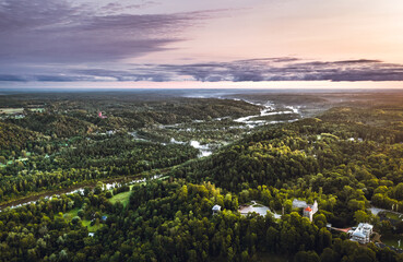 Picturesque valley of Sigulda city in sunrise colors. Panoramic view over pine forest surrounding river Gauja.