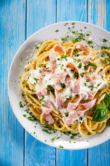 Pasta carbonara on white plate on wooden table
