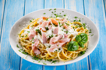 Pasta carbonara on white plate on wooden table
