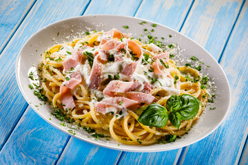 Pasta carbonara on white plate on wooden table
