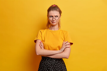 Studio shot of dissatisfied offended girlfriend keeps arms folded and looks unhappily away has bad...