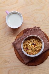 Fresh milk in a mug and muesli with raisins and berries in a ceramic small bowl