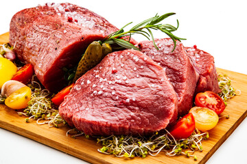 Fresh raw beef on cutting board with fresh vegetables on white background
