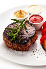 Barbecue beef steak with fresh tomatoes and cucumbers, mustard, mayonnaise and ketchup on white background
