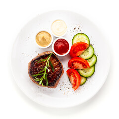 Barbecue beef steak with fresh tomatoes and cucumbers, mustard, mayonnaise and ketchup on white background
