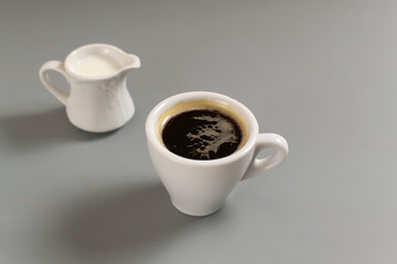 White cup with espresso and cream on a gray background. Close-up. Selective focus. Copy space.