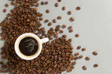 White cup with espresso among coffee beans on a gray background. Close-up. Selective focus. Copy...