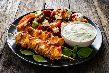 Fried souvlaki, greek salad and tzatziki on wooden table