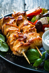 Fried souvlaki, greek salad and tzatziki on wooden table